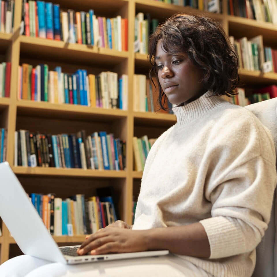 Student is working on a laptop in a university library